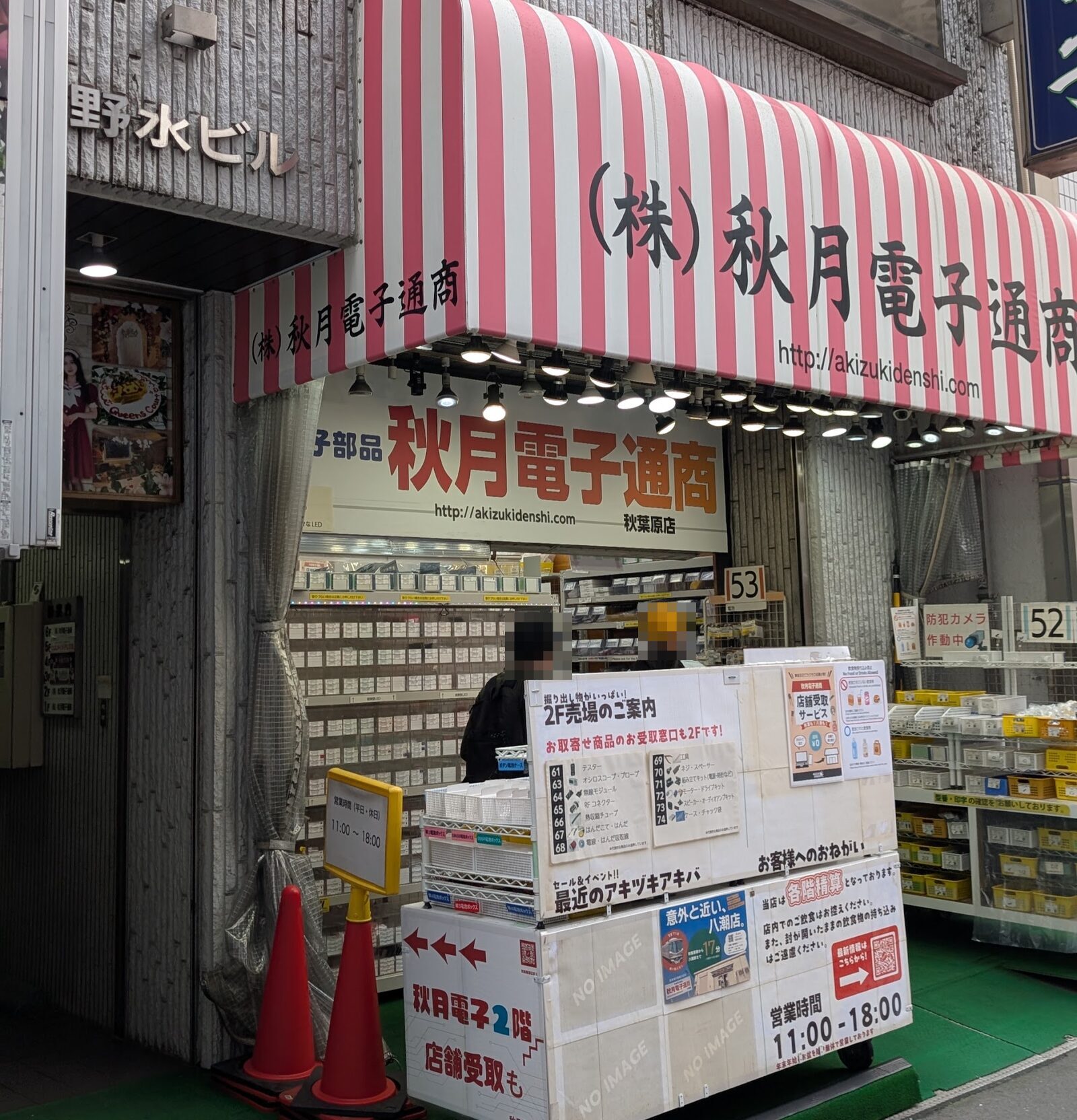 秋月電子通商 秋葉原店の店先。赤と白の縞のテントに店名が出ており、奥は壁一面が部品の引き出しで埋まっている。