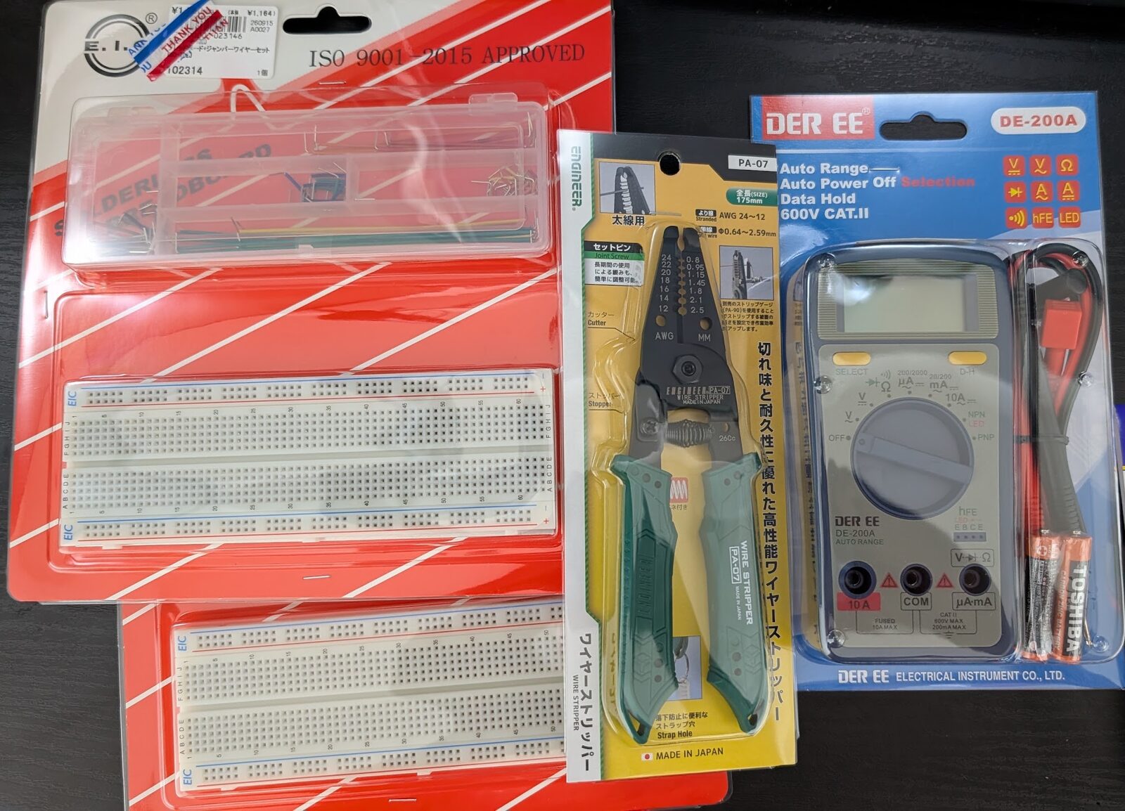 机に並べた工具。830 穴のブレッドボードとジャンパワイヤのセットが 2 組、ワイヤーストリッパー、オートレンジのデジタルマルチメータ。