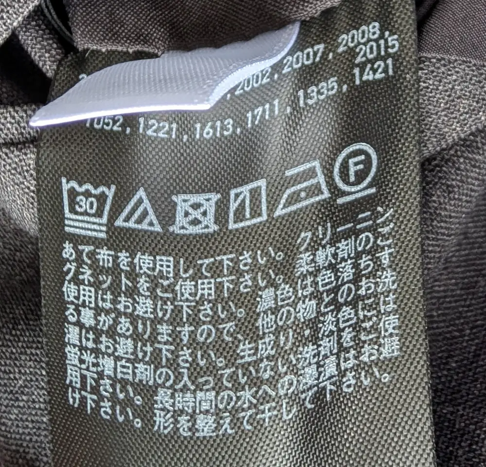 洗濯タグに並んだ記号。左から、液温 30 ℃ までの非常に弱い洗濯、酸素系漂白剤のみ可、タンブル乾燥禁止、つり干し、低温でのアイロン、石油系溶剤でのドライクリーニング可